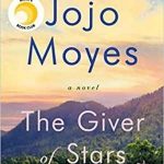 Book cover of The Giver of Stars by Jojo Moyes. A landscape of a green field with a mountain in the background with a beautiful yellowish sky. There is a woman on a horse, but she is very small by one of the trees.